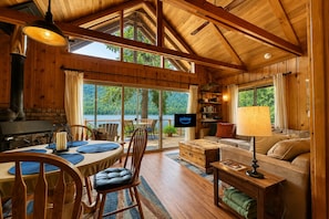 A cozy cabin interior with a dining area, a sofa, and a television.