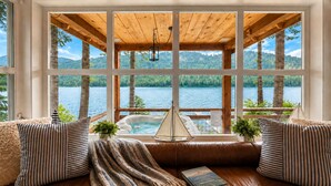 A cozy room with a large window overlooking a lake, a hot tub, and a wooden ceiling. - Doc Roy's Legacy On Fish Lake Home by NW Comfy Cabins by RedAwning (Leavenworth)