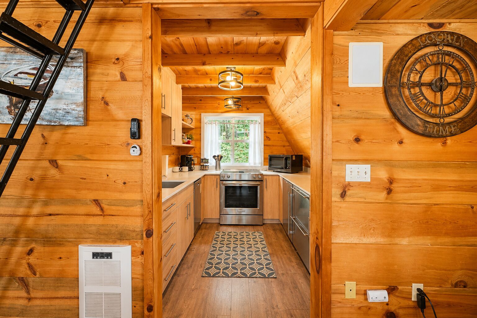 Interior de una cabaña de madera con cocina, un reloj y una escalera.