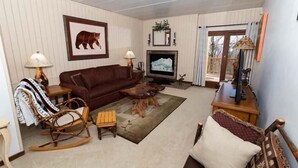 A cozy living room with a brown sofa, a wooden rocking chair, a coffee table, and a television.