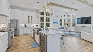 A spacious kitchen with white cabinetry, a central island, and a dining area with a white sofa and coffee table. - Blue Mountain Beach | Pool | Bikes (Santa Rosa Beach)