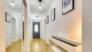 A hallway with a piano, framed pictures on the walls, and a door at the end.