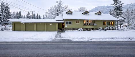 A two-story house with a garage, a covered driveway, and a snow-covered landscape.