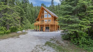 A log cabin with a balcony, surrounded by dense forest. - Bearfoot Chalet 3 Bedroom Home by NW Comfy Cabins (Leavenworth)