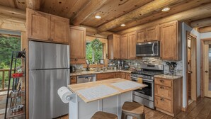 A modern kitchen with wooden cabinets, stainless steel appliances, and a central island with stools. - Bearfoot Chalet 3 Bedroom Home by NW Comfy Cabins (Leavenworth)