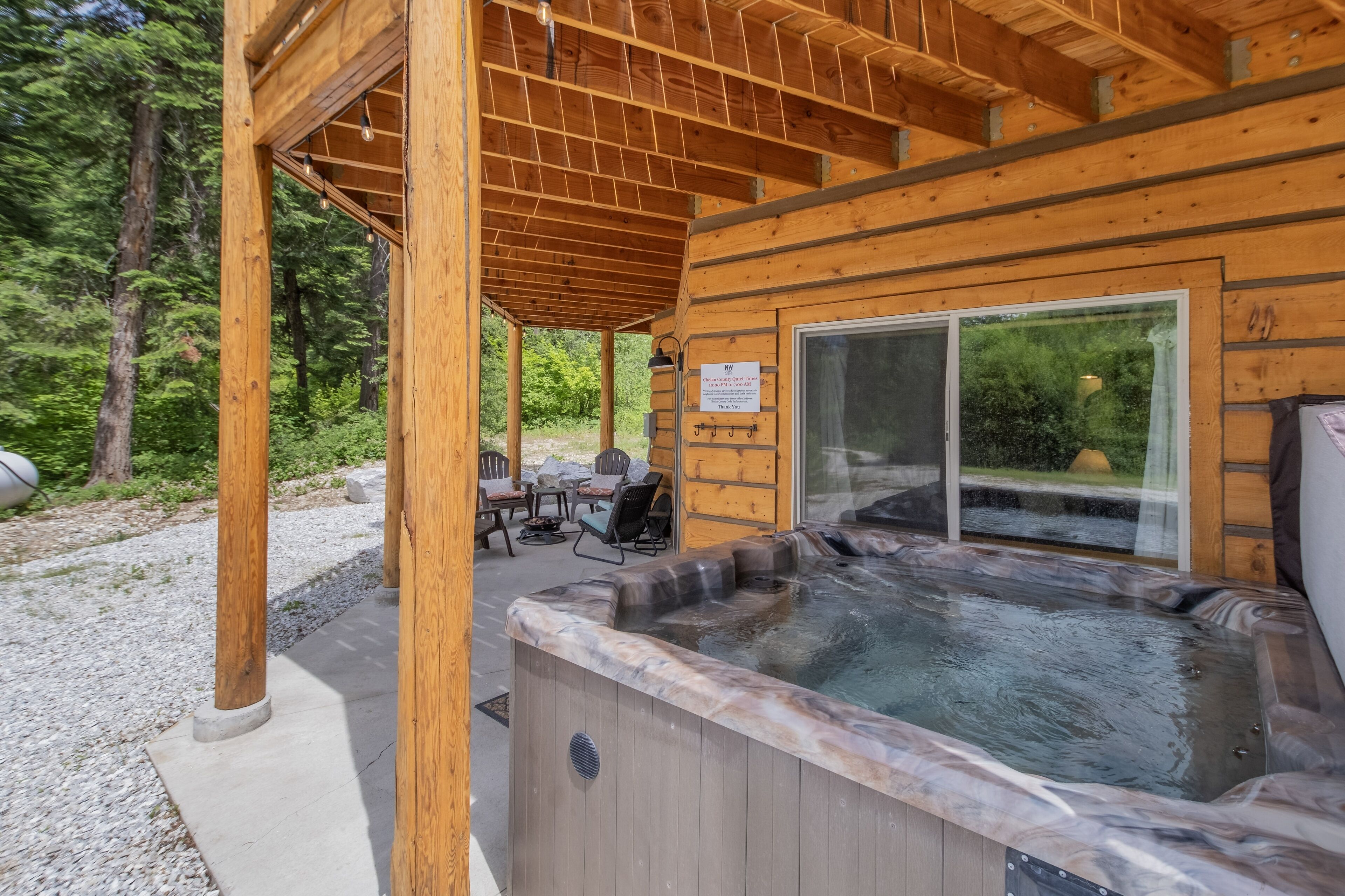A wooden cabin with a hot tub, outdoor seating, and a glass door leading to a deck.