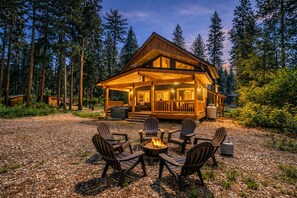 A lodge with a wooden exterior, a deck, and a fire pit surrounded by Adirondack chairs. - Compass Cabin 2 Bedroom Homeby NW Comfy Cabins by RedAwning (Leavenworth)
