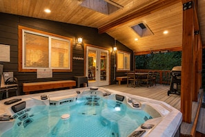 Ein Whirlpoolbereich mit Holzterrasse, einer überdachten Sitzgelegenheit und Blick ins Freie.