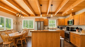 Una cocina con armarios de madera, una isla central, un comedor con sillas y un ventanal grande.