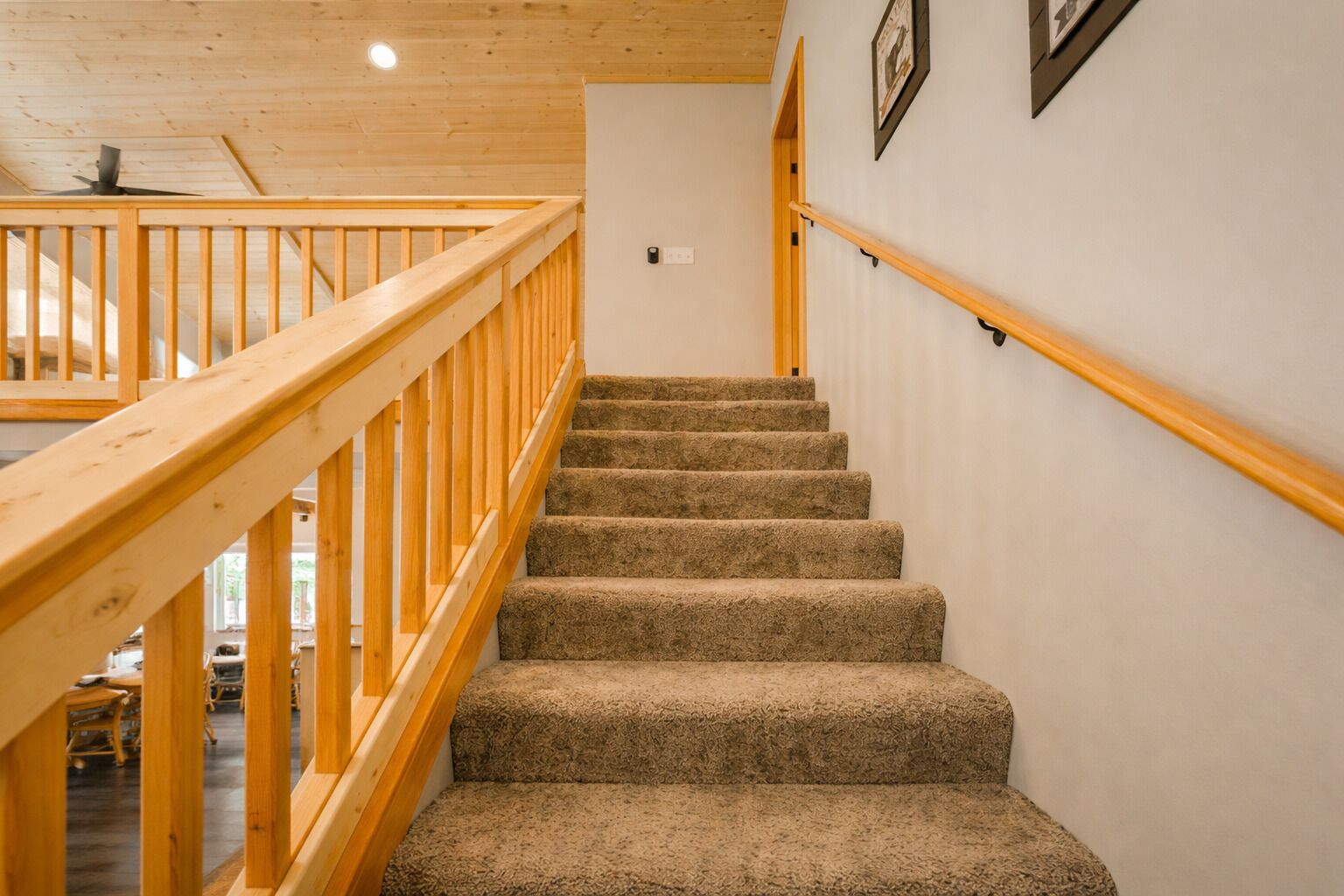 Un escalier en bois, dont les marches sont recouvertes de moquette, mène à l’étage supérieur.