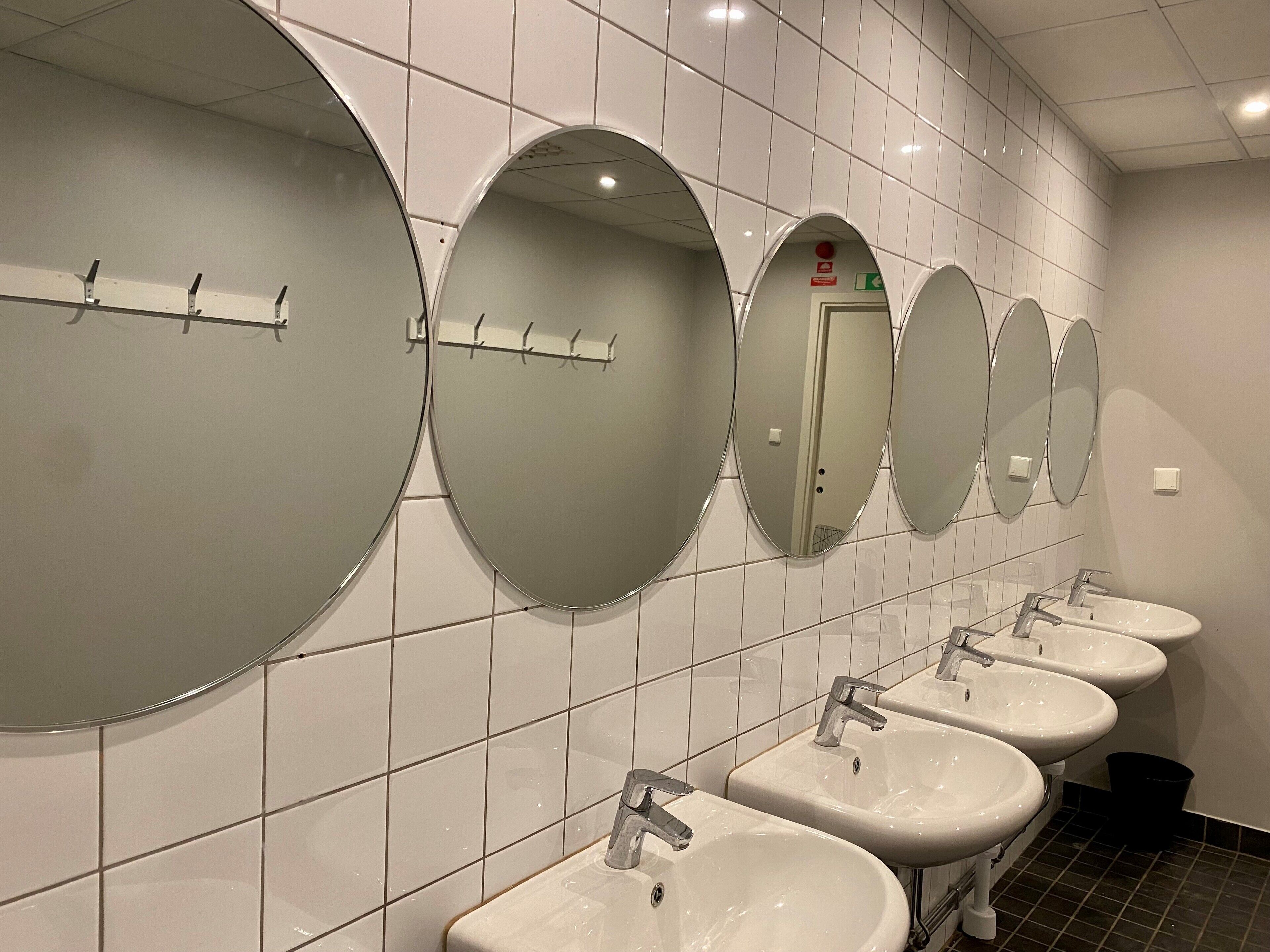 A row of six sinks with mirrors above them in a restroom.