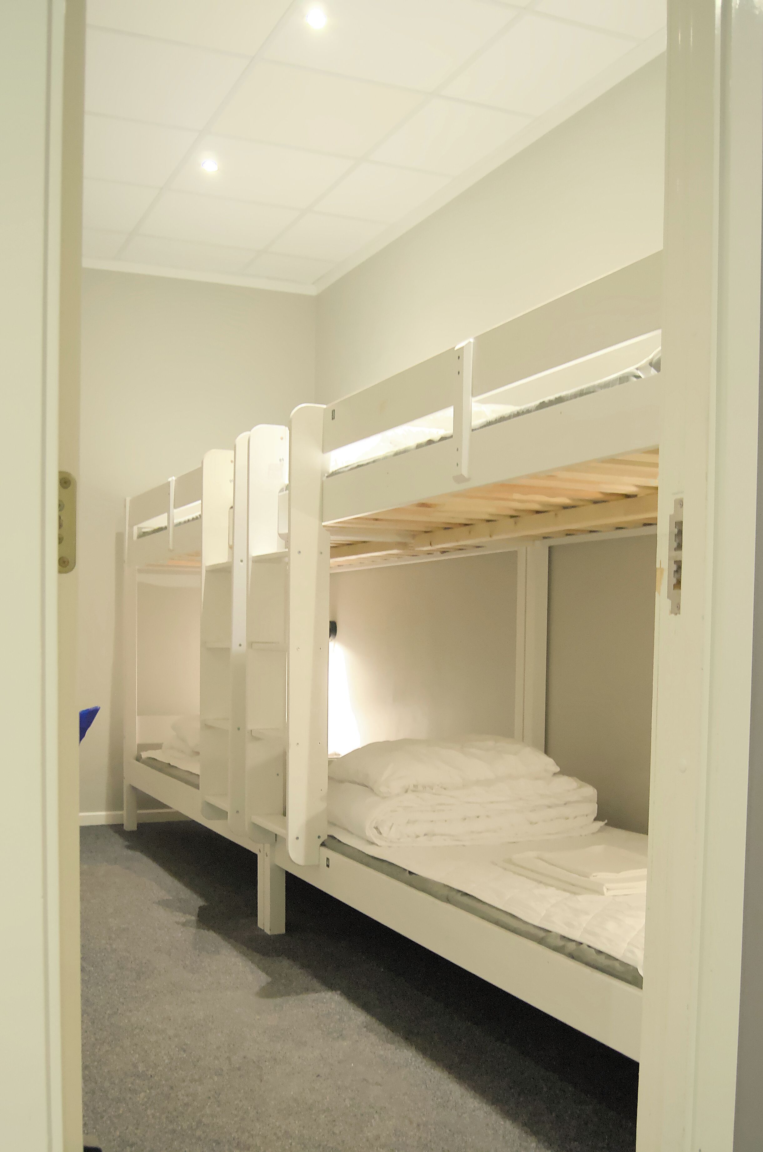 A bunk bed room with white walls and a grey carpet.