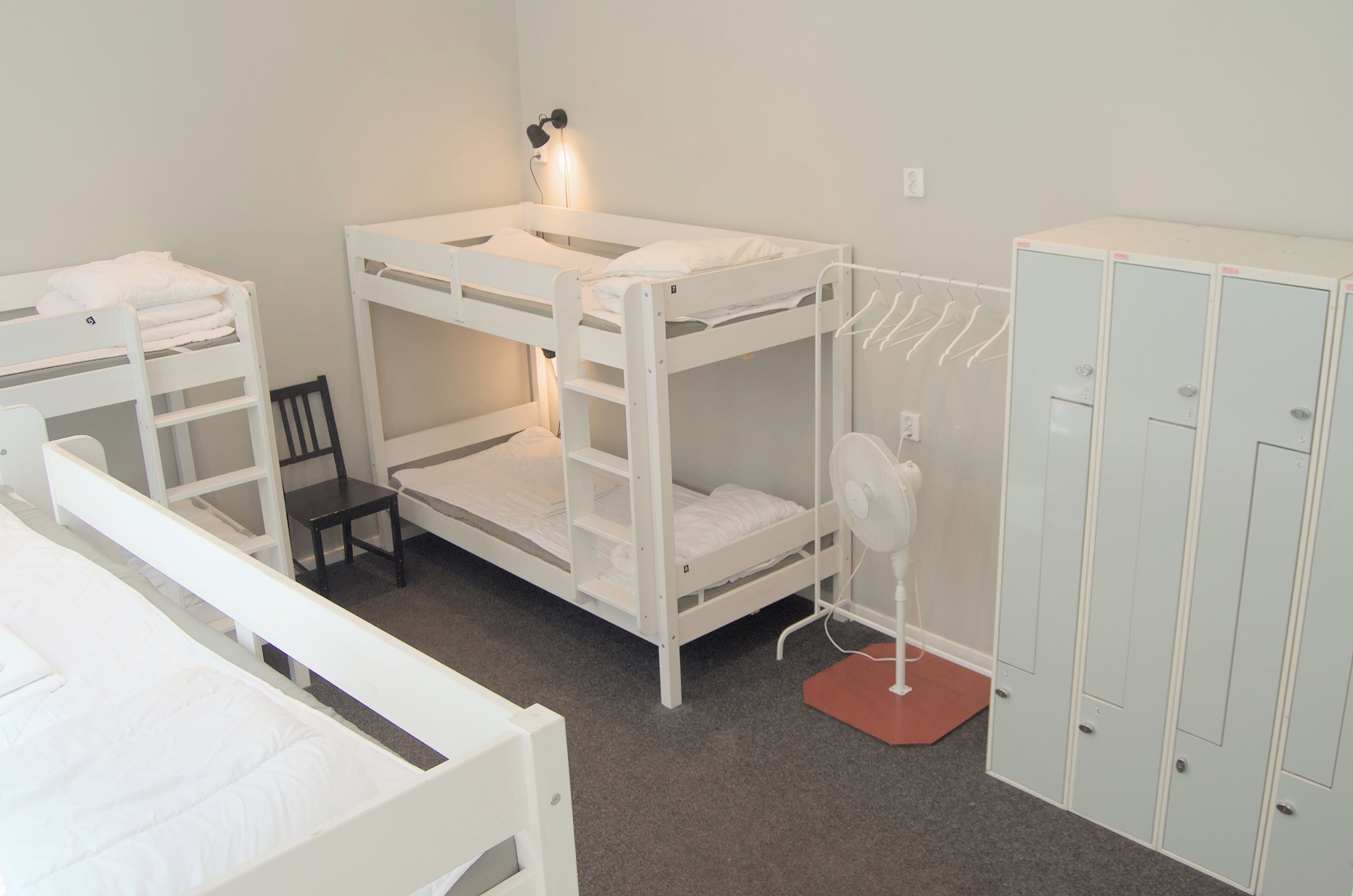 A bunk bed room with a desk, a chair, and a wardrobe.