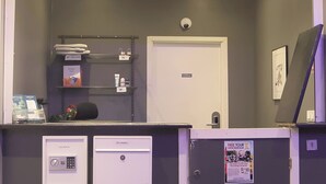 Un comptoir d’accueil avec un plan de travail blanc, une porte portant l’inscription « Bureau », et une affiche faisant la publicité d’une visite guidée gratuite.