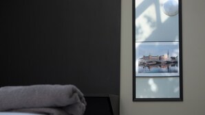 Une chambre d’hôtel avec un lit, une fenêtre donnant sur un paysage urbain encadré et une table de chevet.