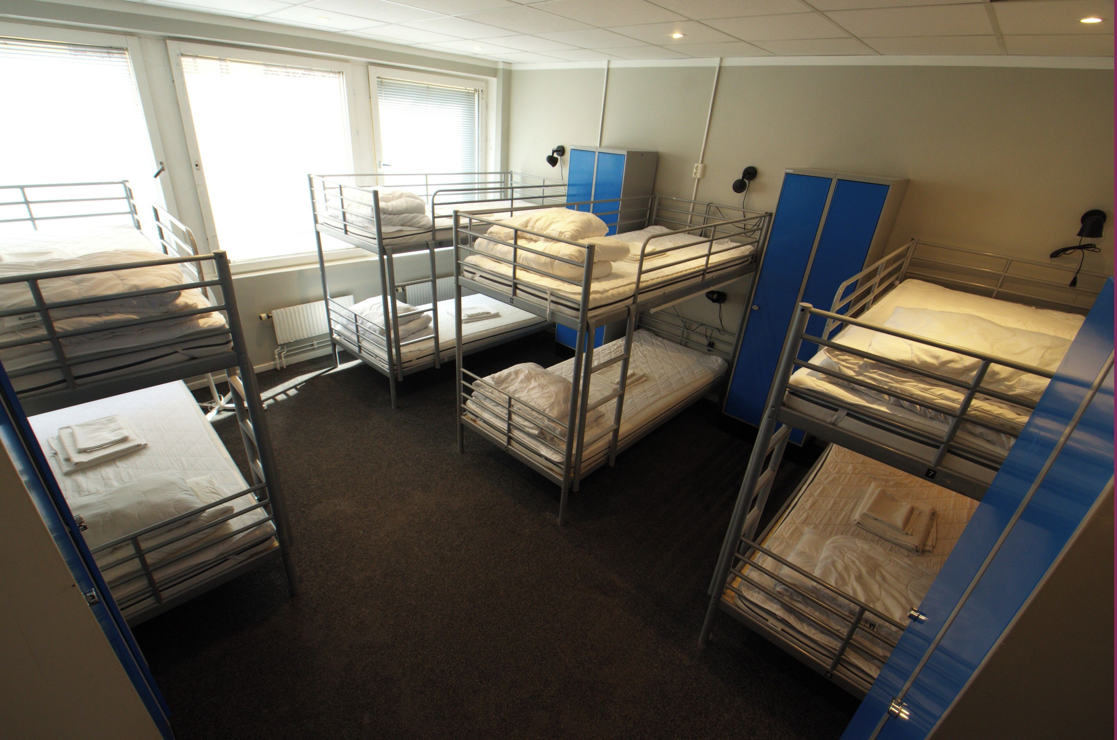 A dormitory room with bunk beds, a radiator, and a window.