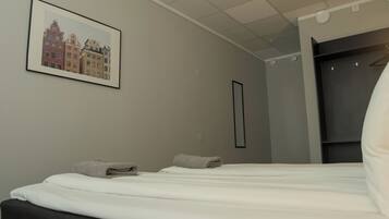 Una habitación de hotel con cama, un cuadro enmarcado de edificios, un armario y un espejo.