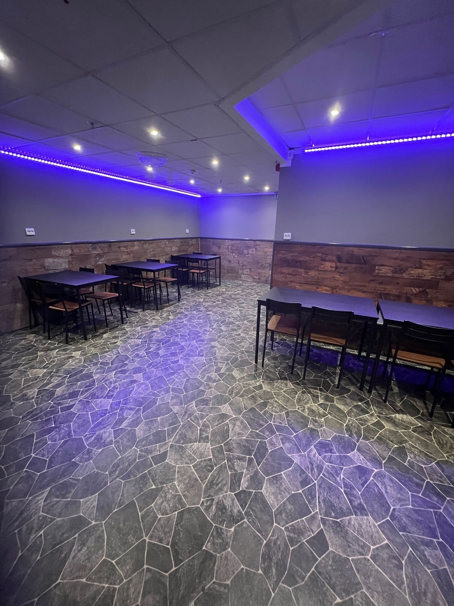Sala de conferências com piso de pedra, mesas e cadeiras.