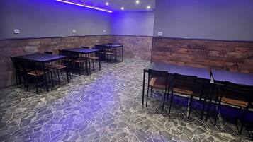 Sala de conferências com piso de pedra, mesas e cadeiras.