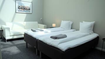 Una habitación de hotel con una cama, un sofá, una mesita de noche con una lámpara y un cuadro enmarcado en la pared.