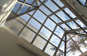 Un tragaluz con estructura geométrica y vista al cielo a través del vidrio.
