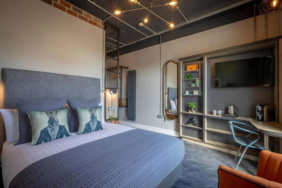 Una habitación de hotel moderna con una cama grande, un escritorio y una zona de estar.