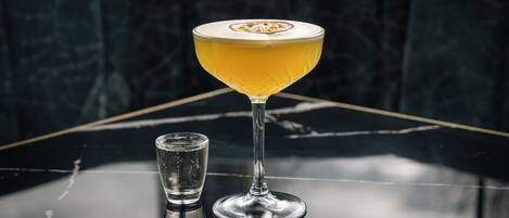 A cocktail in a stemmed glass on a reflective surface.