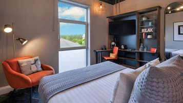 Una habitación de hotel moderna con una cama grande, un escritorio, una silla y una estantería.
