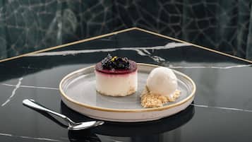 A dessert on a plate with a spoon, set on a reflective black table with a geometric pattern in the background.