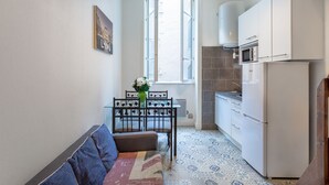 Een kleine keuken met een eettafel, een bank en een raam.