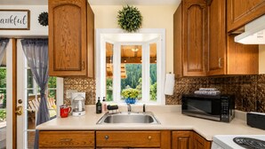 A kitchen with wooden cabinets, a stainless steel sink, a coffee maker, a microwave, and a stove.