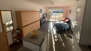Kompakti keittiö, jossa on ruokailutila, suuri ikkuna ja liukuovi, joka johtaa ulkoilmassa olevalle parvekkeelle.
