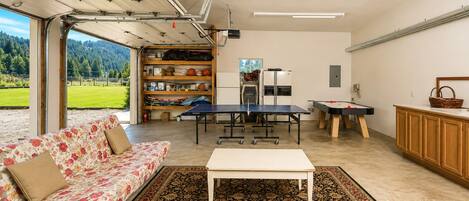 A spacious living area with a sofa, a coffee table, a ping pong table, and a pool table.