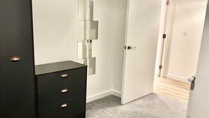 A bedroom with a bed, a black wardrobe, and a white door. - Captivating 2-bed Apartment in London (London)
