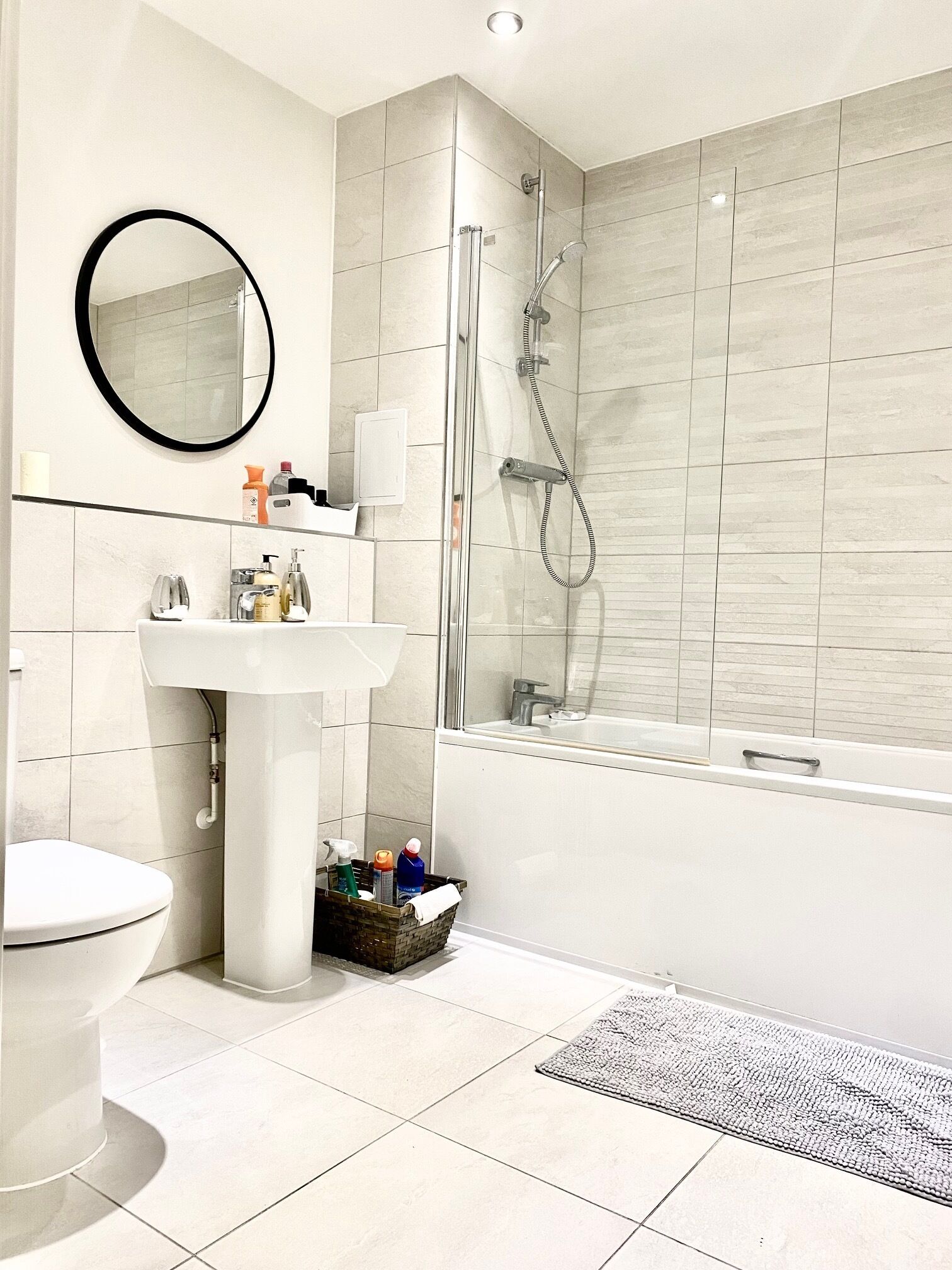 Een moderne badkamer met een wit wastafelmeubel, spiegel, toilet en een douchecabine met glazen wanden.