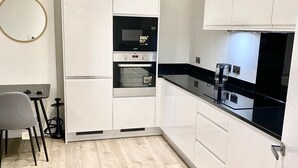 A modern kitchen with white cabinetry, a black countertop, and a built-in oven. - Captivating 2-bed Apartment in London (London)