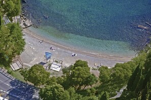 Eine Luftaufnahme eines Strandes mit klarem Wasser, einem Spielplatz und umgebender Bepflanzung.