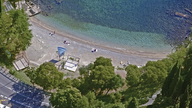 An aerial view of a beach with clear water, a playground, and surrounding greenery. - Bruk in Lovran - Kvarner Region / Bruk in Lovran - Appartement für 2 Personen AP2 (Lovran)