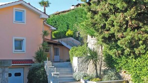 A two-story building with a stone staircase leading to a door, surrounded by lush greenery and a hillside. - Bruk in Lovran - Kvarner Region / Bruk in Lovran - Appartement für 2 Personen AP2 (Lovran)