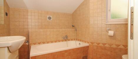 Ein Badezimmer mit einer Badewanne, einer Toilette und einem Waschbecken.