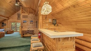 A log cabin interior with a bar area, wooden walls, a ceiling fan, and a chandelier. - Soaring Pines Lodge 1 Bedroom Home by NW Comfy Cabins by RedAwning (Leavenworth)