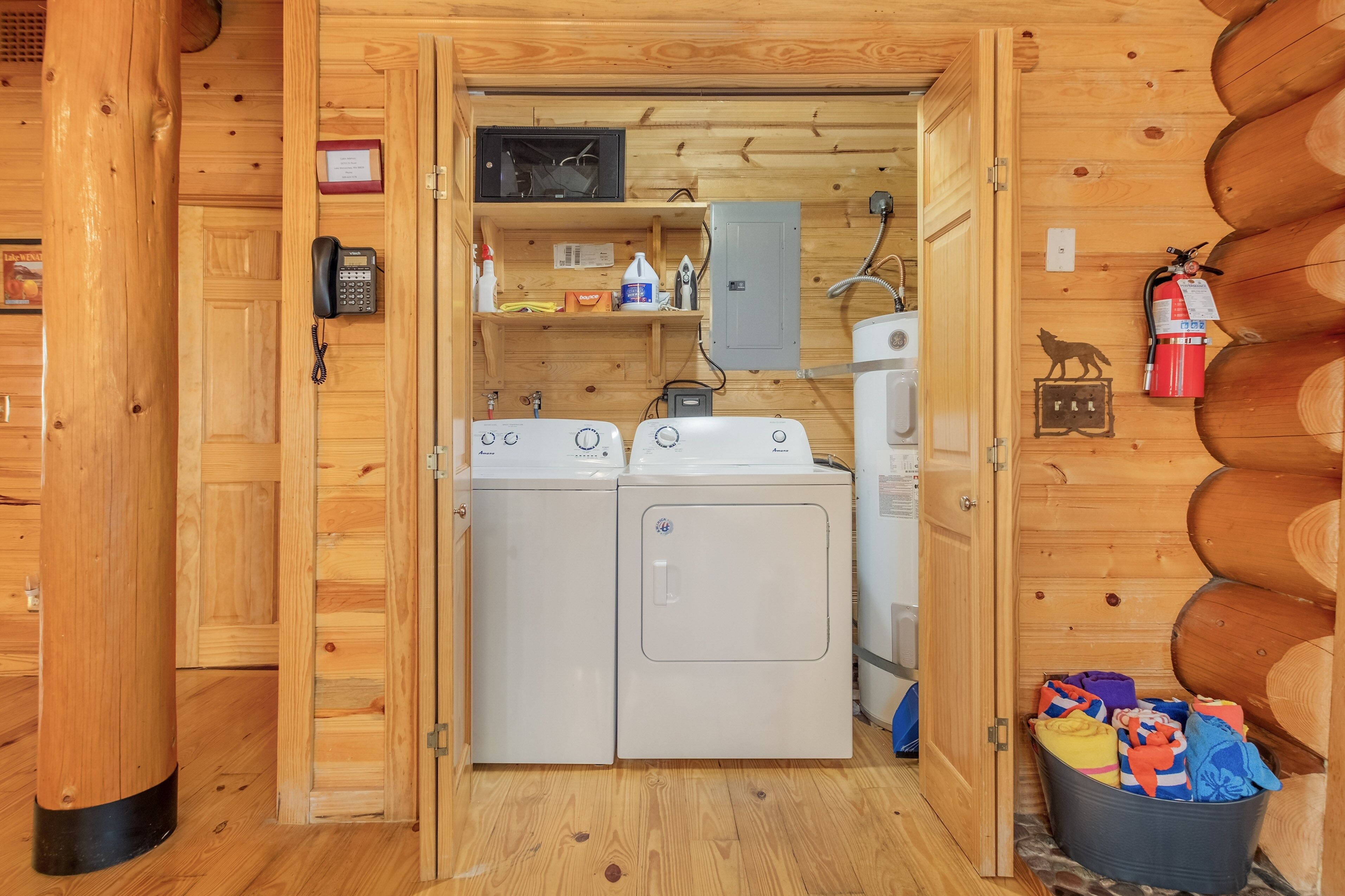 A wooden cabin interior with a laundry area featuring two washing machines and a sink.