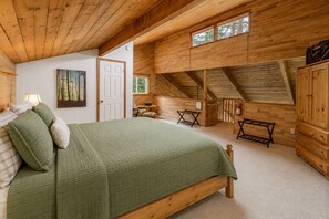 A bedroom with a bed, a nightstand, a chair, a window, and a door.