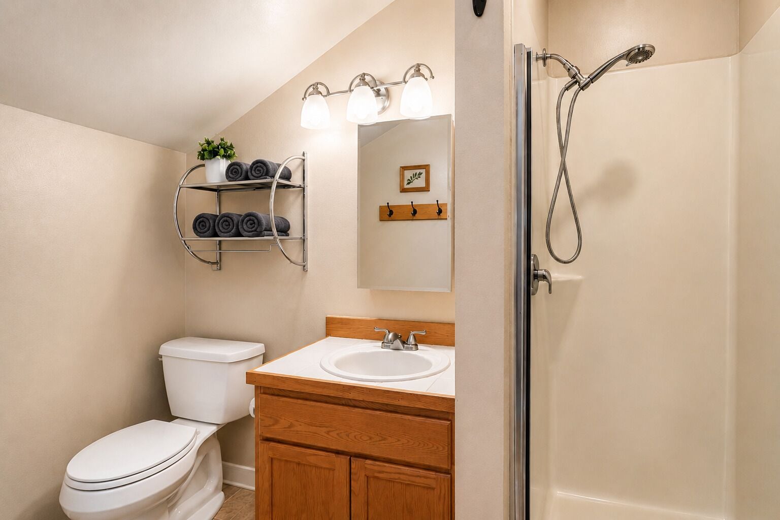 A bathroom with a toilet, sink, shower, and towel rack.