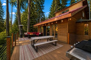 Une cabane en bois dotée d’une terrasse, d’un espace salon extérieur et d’un barbecue.