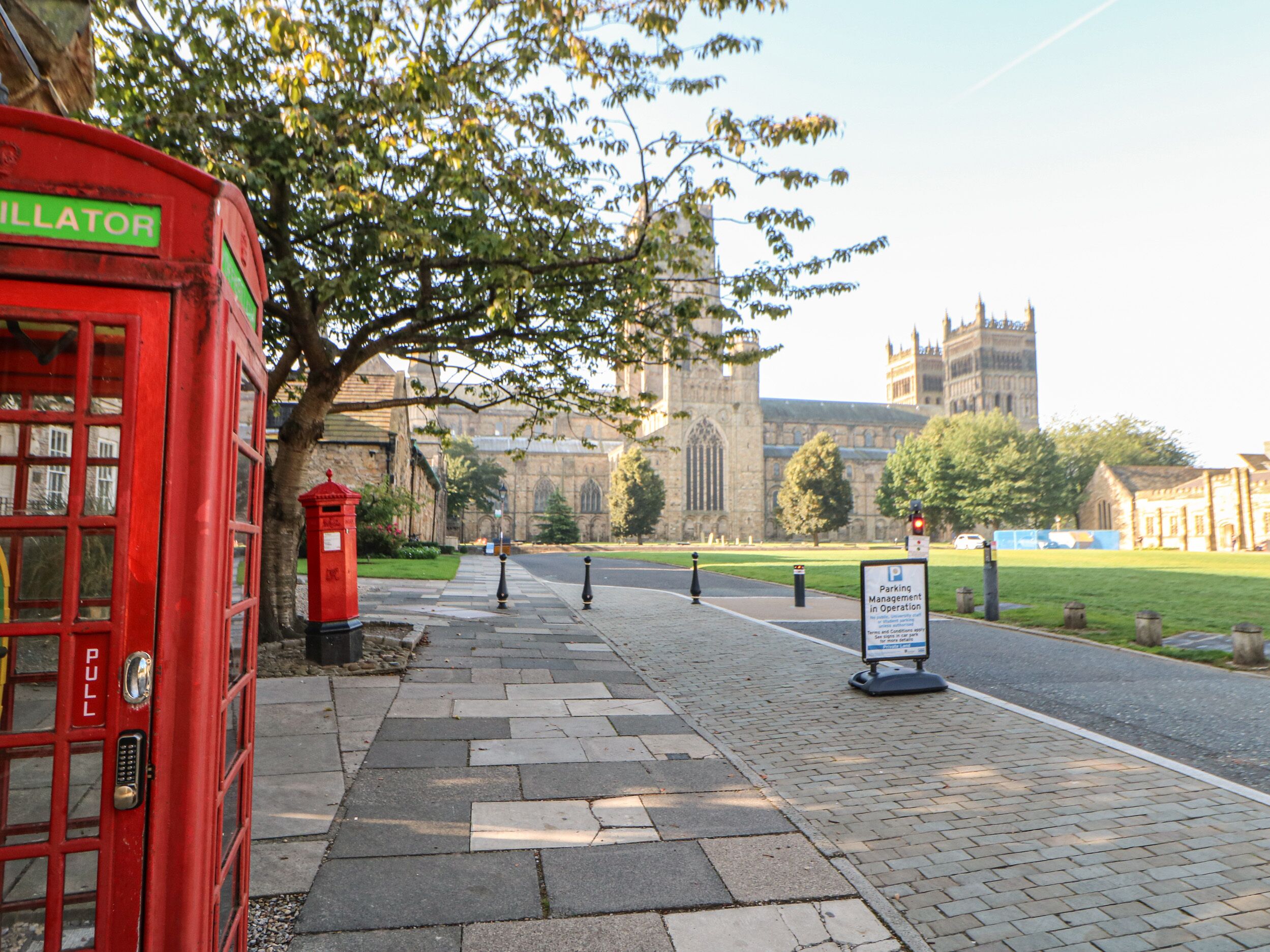 A red telephone booth, a sign for parking management, and a historic building in the background.