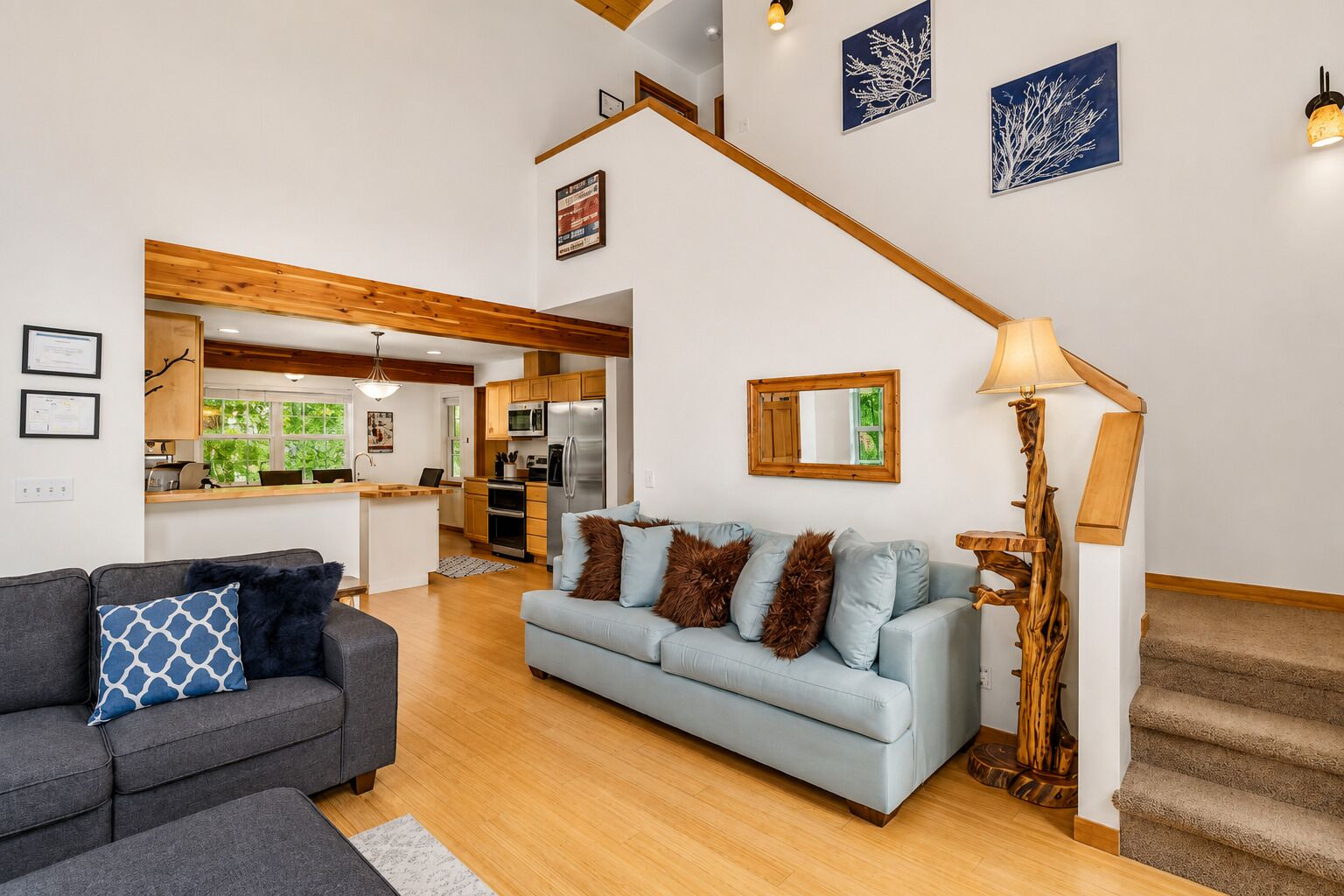 A modern living room with a grey sofa, a light blue sofa, and a staircase.