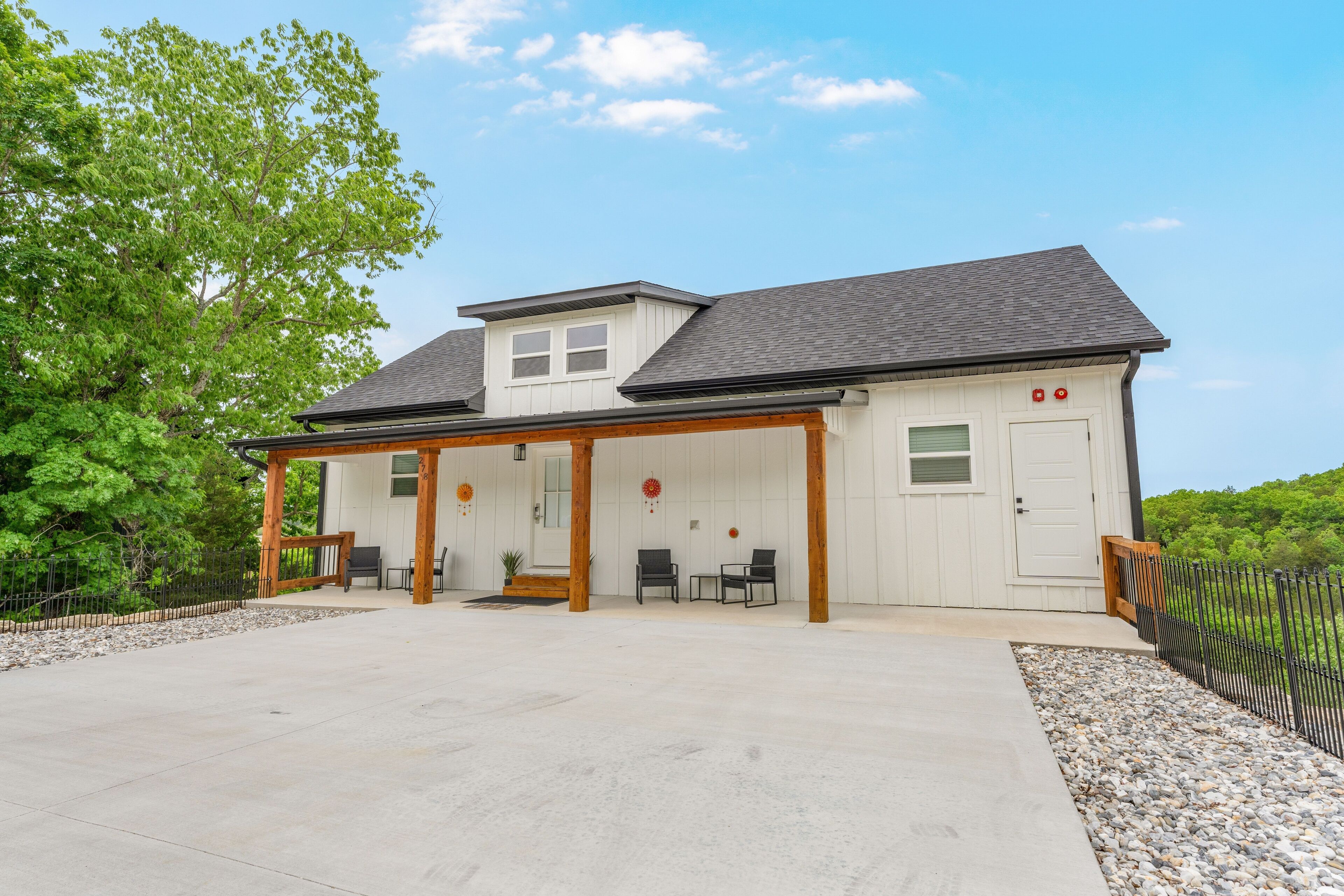 A two-story building with a covered patio area, a small porch, and a front door.