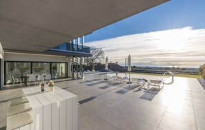 Une terrasse extérieure moderne dotée d’une piscine, de chaises longues et d’un espace repas avec une table et des chaises.