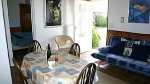 A dining area with a table set for four, a sofa, and a chair. - NEW: Ker Louarn (Ploubezre)